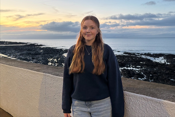Graduate stood in front of a coastline