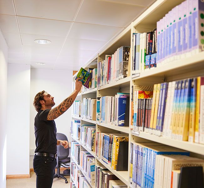 Student taking a book from a shelf in the library