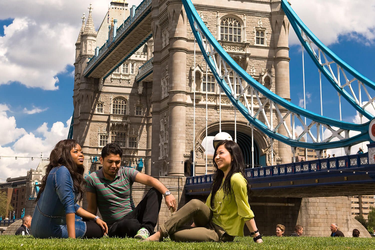 Three University of Sunderland in London students sat on the grass near Tower Bridge