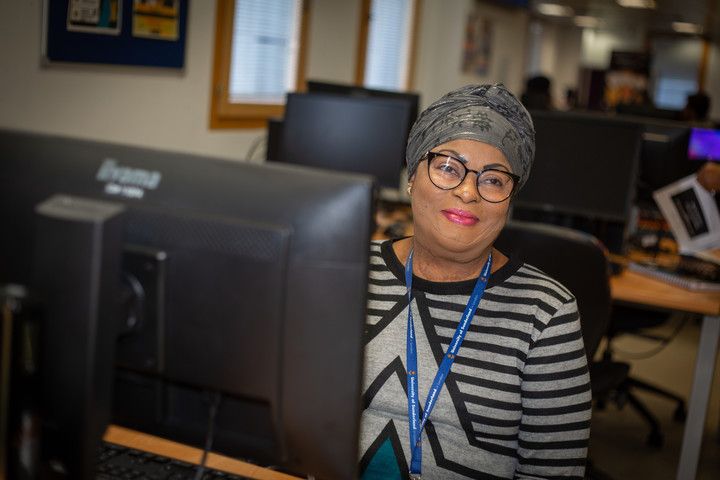 University of Sunderland in London student behind a computer smiling