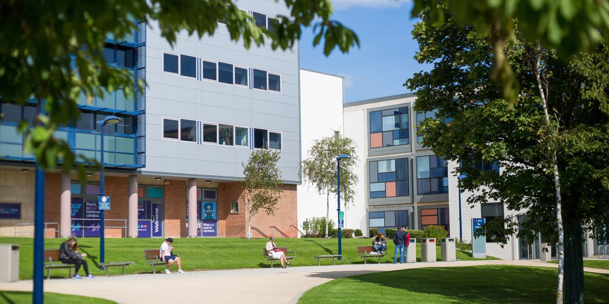 Buildings at our city campus with students sat on benches outside
