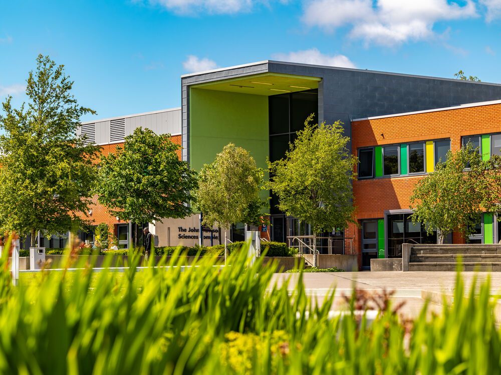 The John Dawson Sciences Complex surrounded by trees on a sunny day