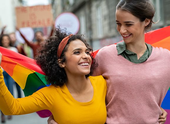 Two women hold up a rainbow flag.