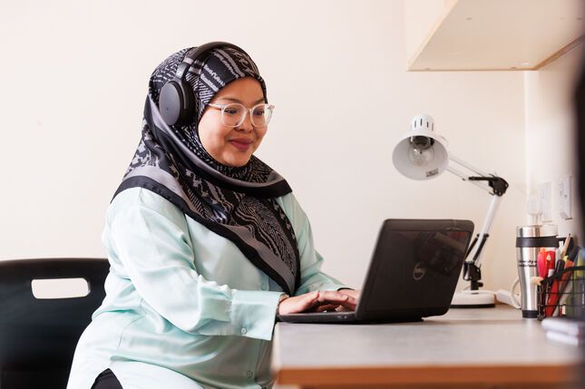 A student working on a laptop with headphones on