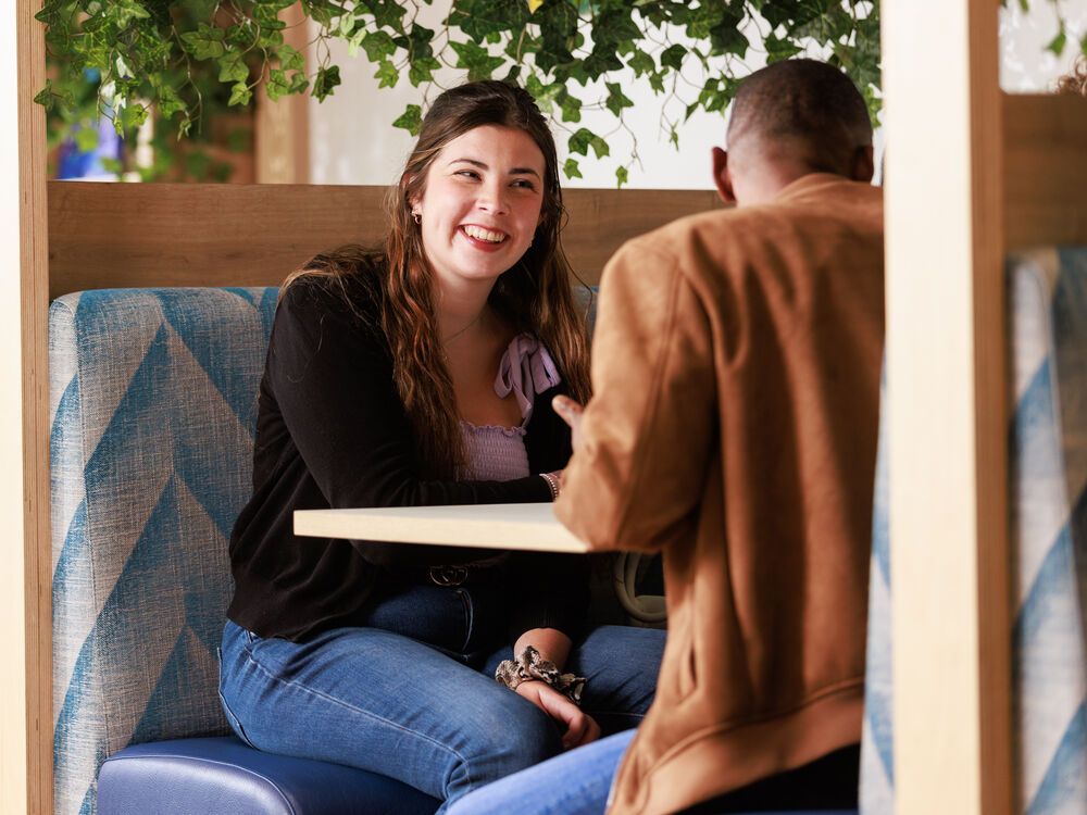 Two students sitting together at a table chatting