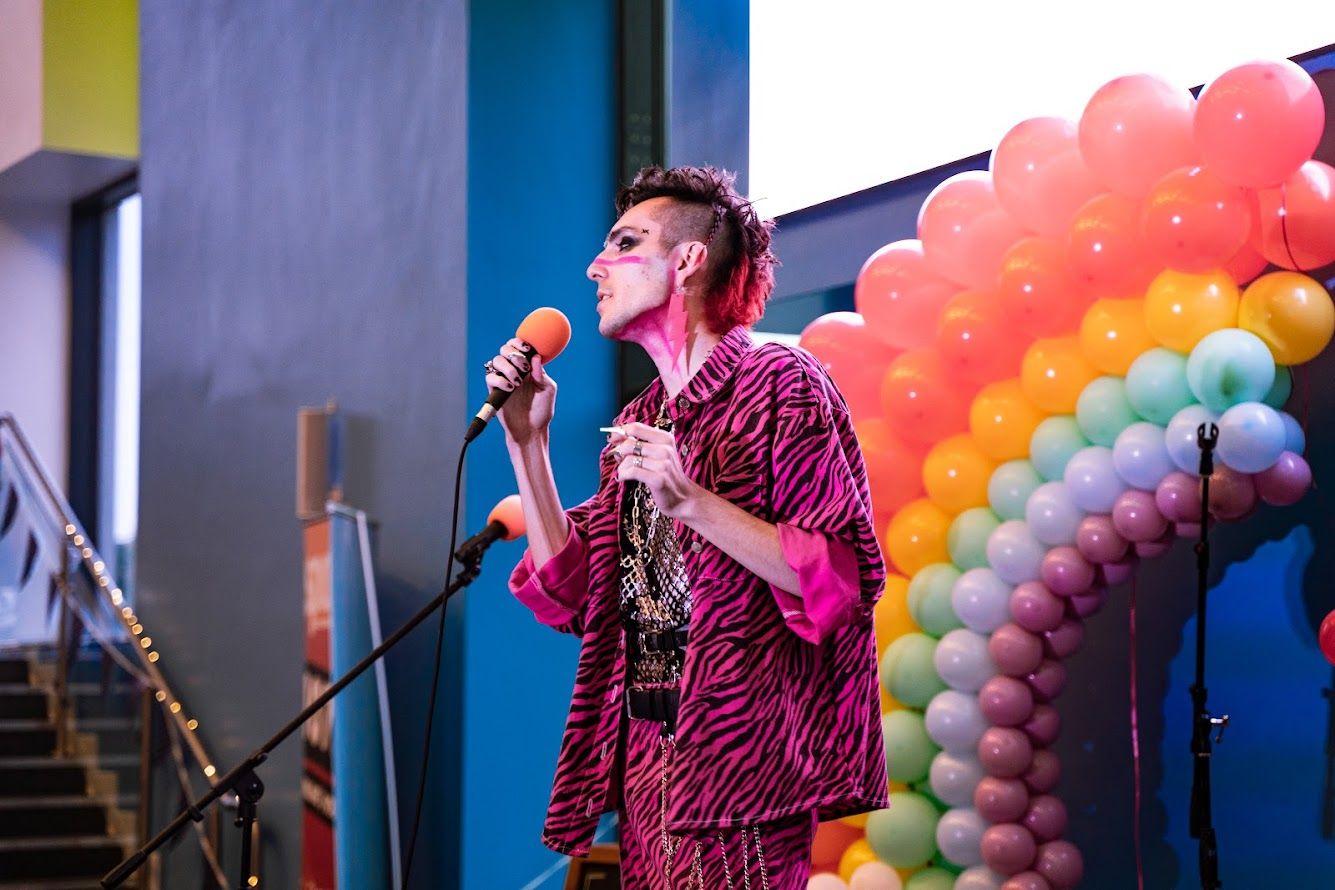 A person speaking into a microphone on stage at the Big Gay festival