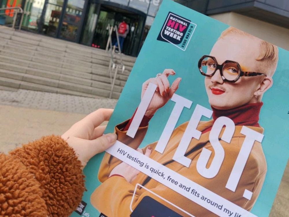 A hand holding a HIV testing leaflet outside City Space