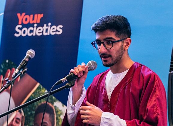 A student speaking into a microphone at the evening of food and prayer to mark the beginning of Ramadan