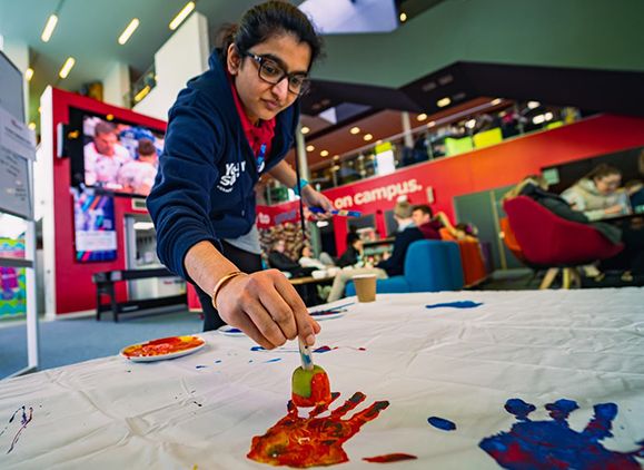 A student painting on a table during Diwali celebrations