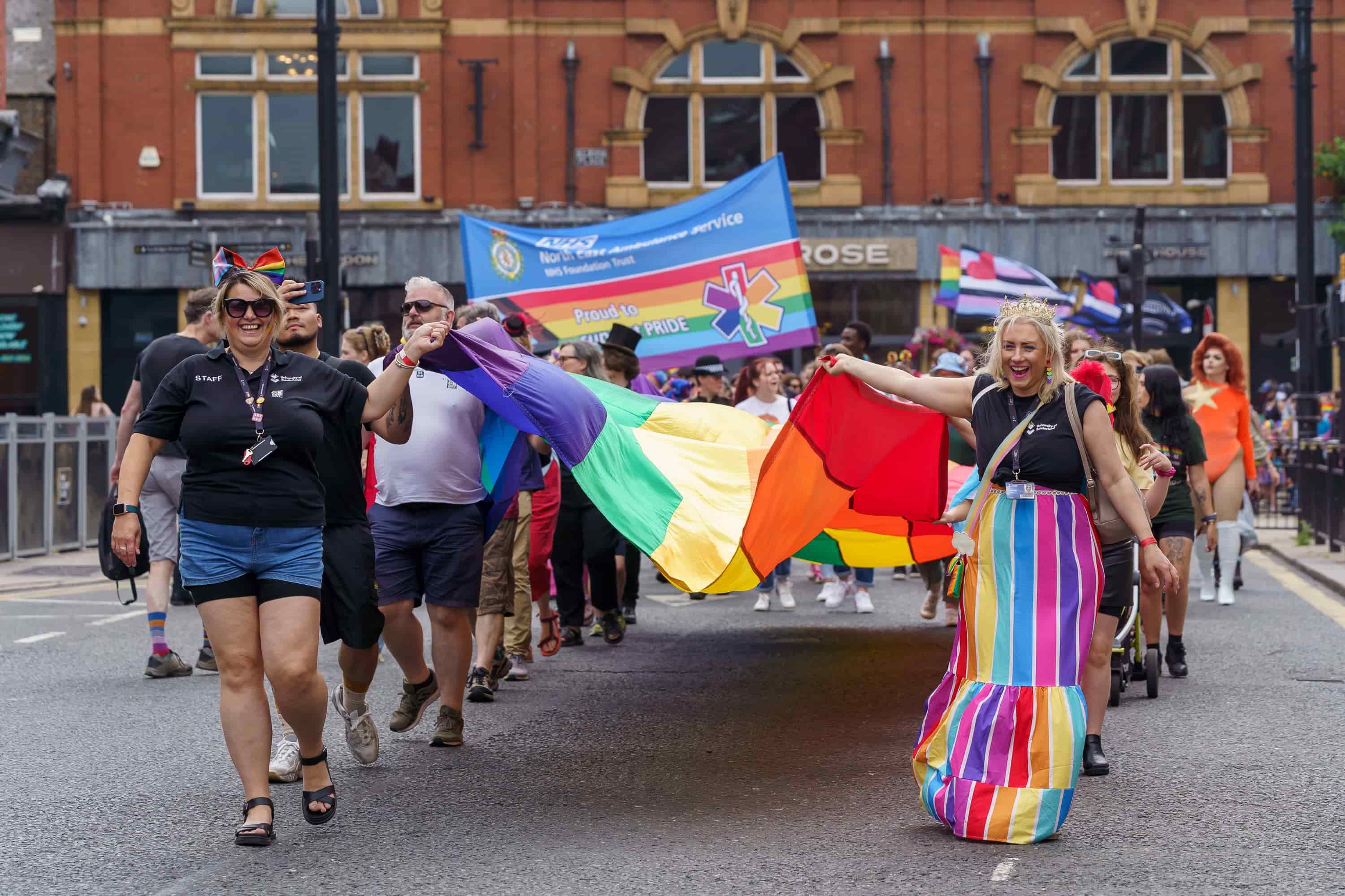 People walking in the Sunderland Pride Parade carrying a rainbow flag