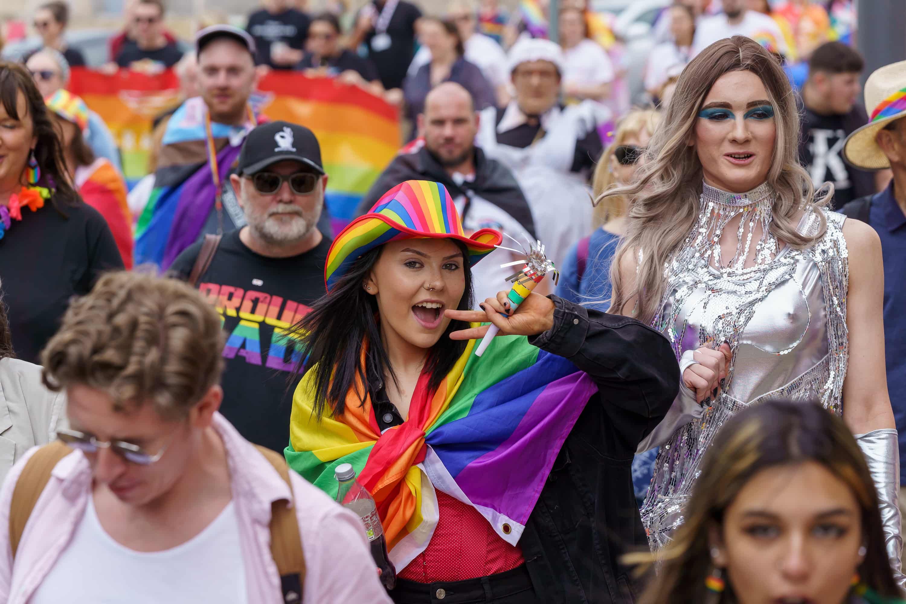 People walking in the Sunderland Pride Parade wearing rainbow flags and accessories