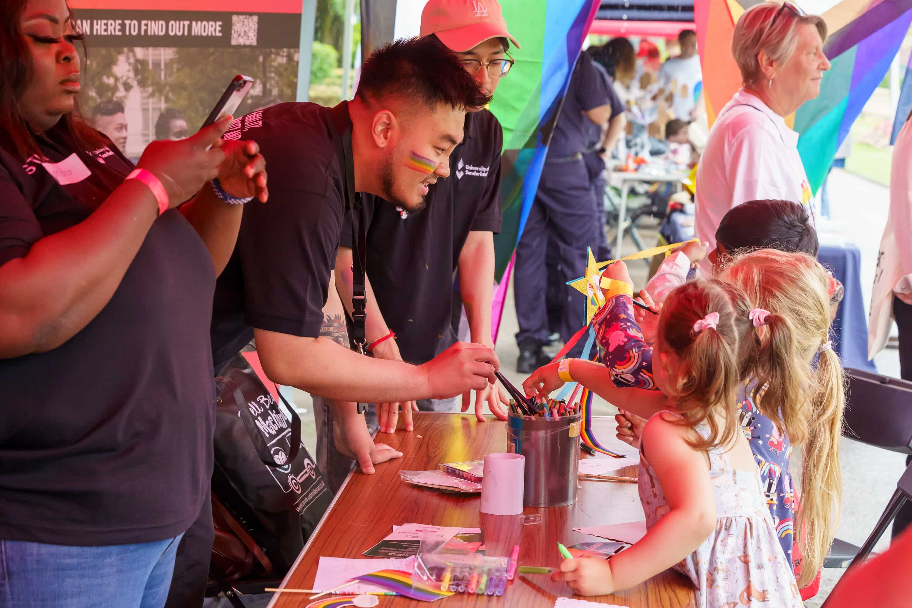 A person speaking to children on a stall at Sunderland Pride