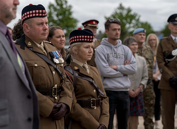 A group of veterans in uniform and visitors at an Armed Forces event