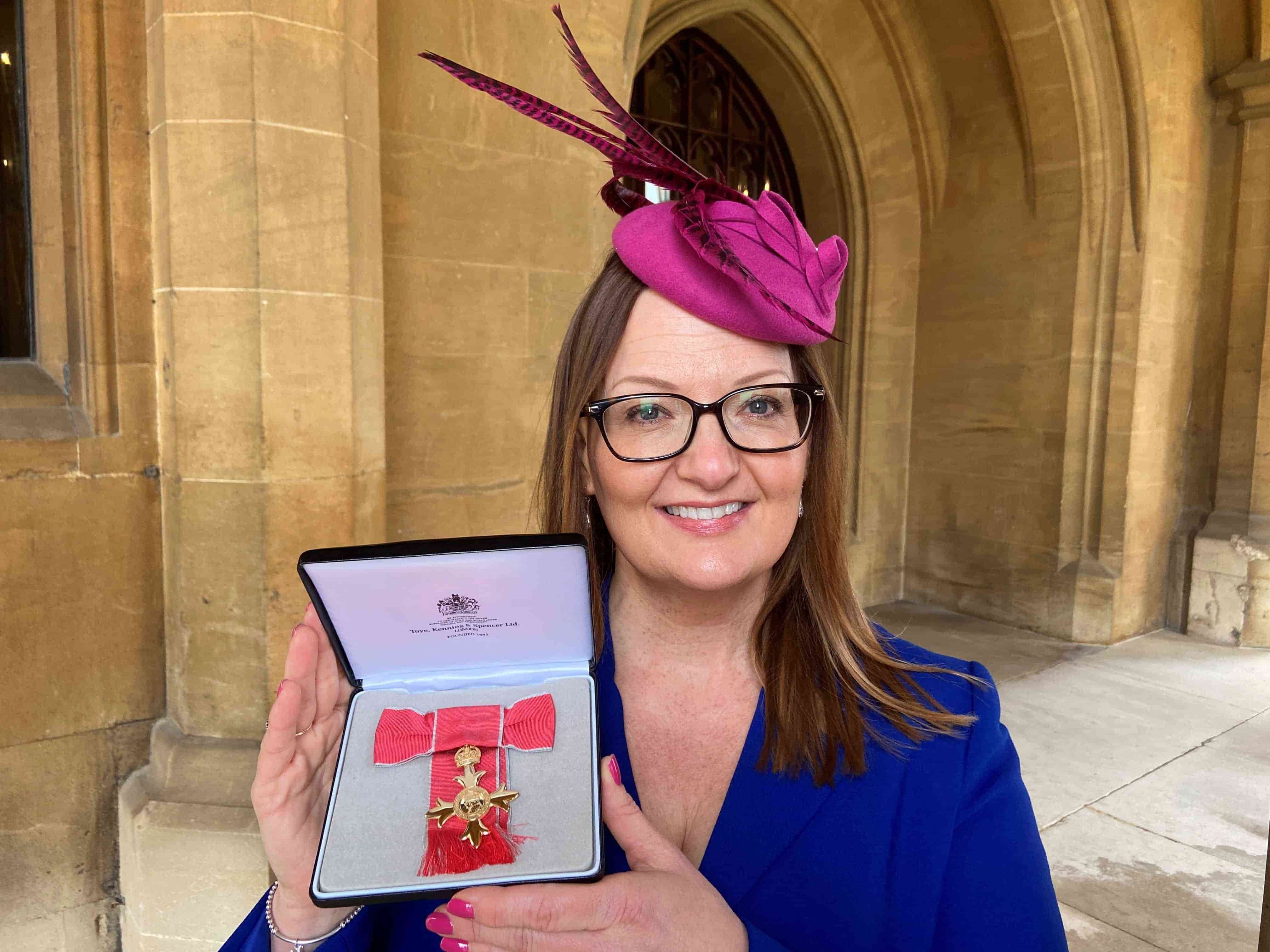 Wendy Price holding her OBE medal