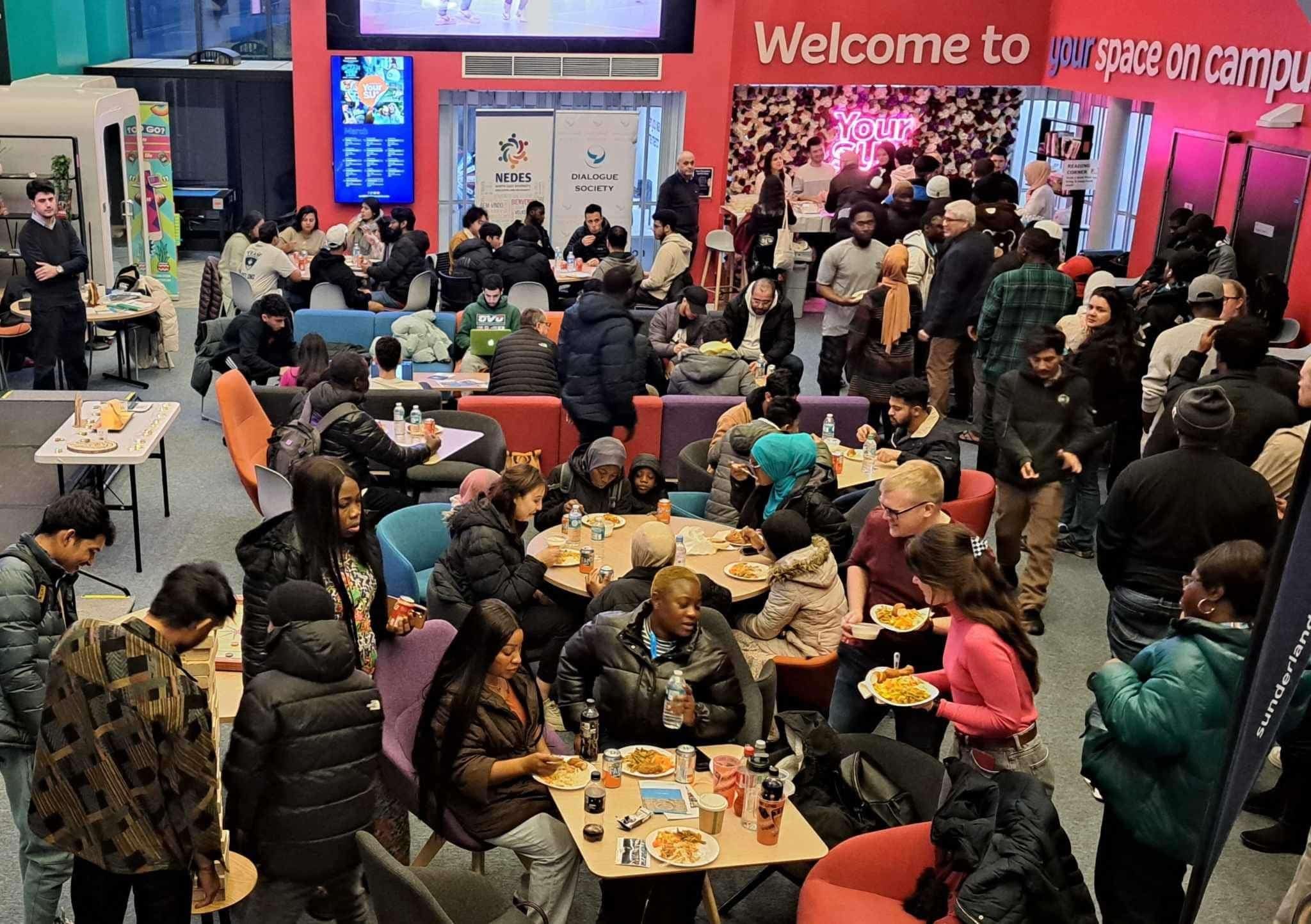 Lots of students gathered together chatting and eating at the Friendship evening in the Students Union