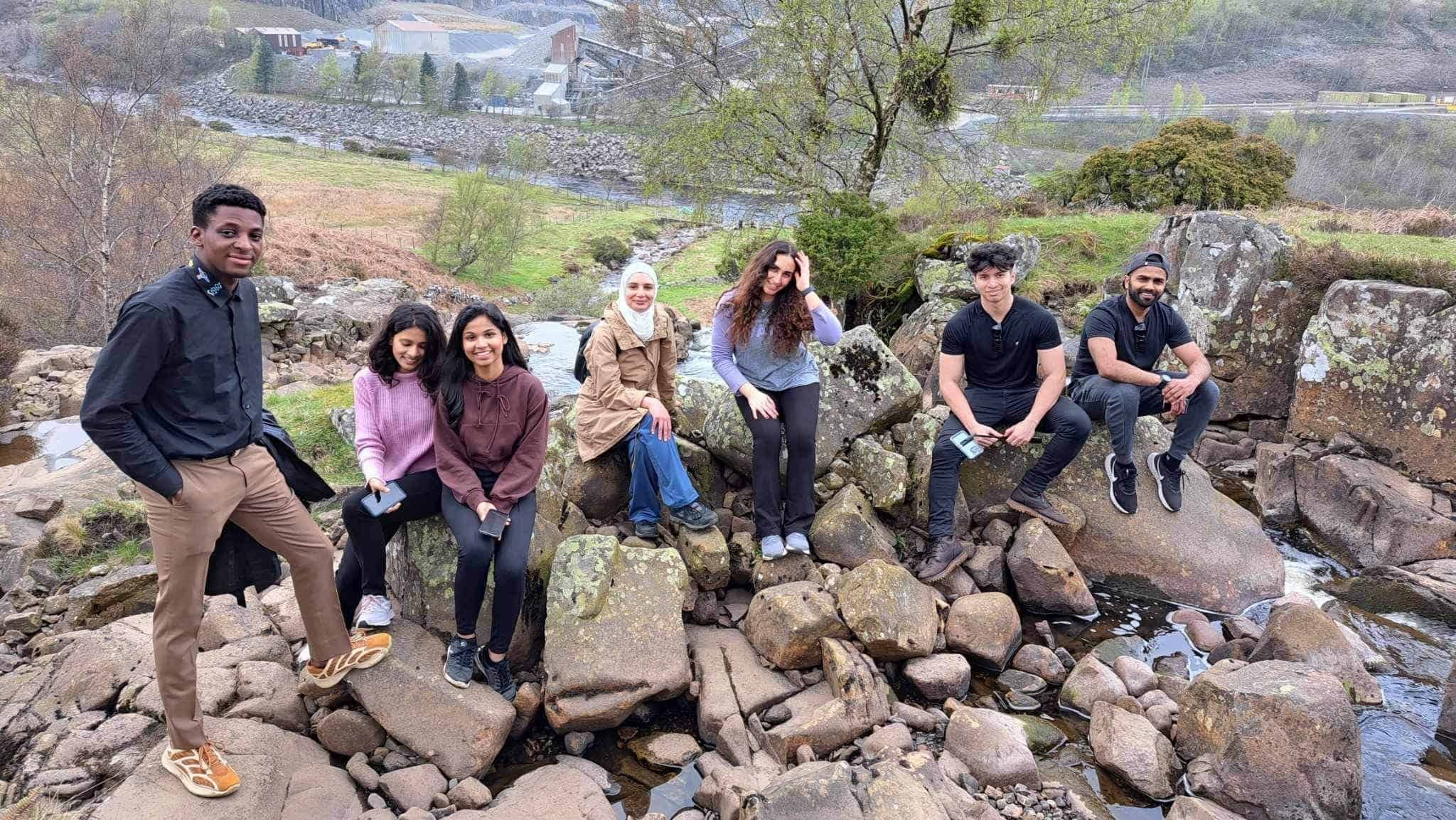 Students sitting on the rocks smiling for the camera