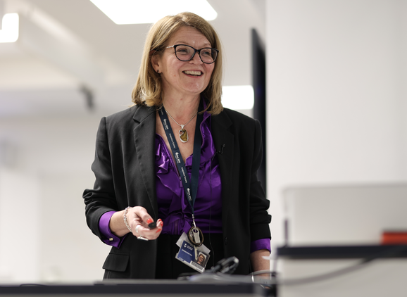 A lecturer presenting at the front of a class smiling