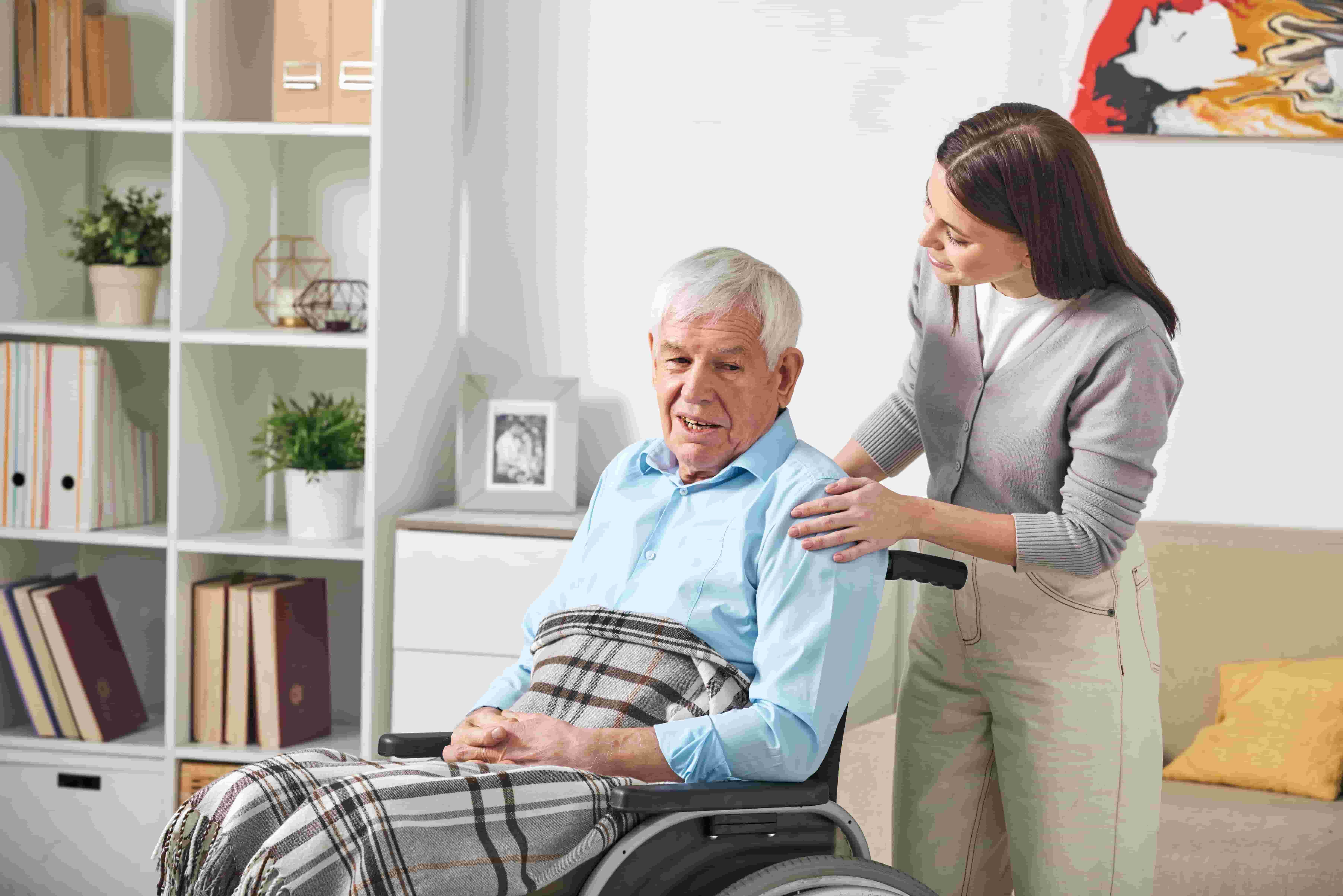 An elderly person in a wheelchair speaking to their carer who is standing behind them