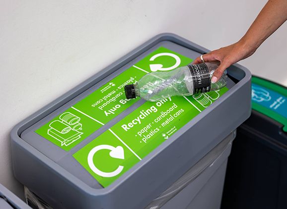 A plastic bottle being placed into recycling bin