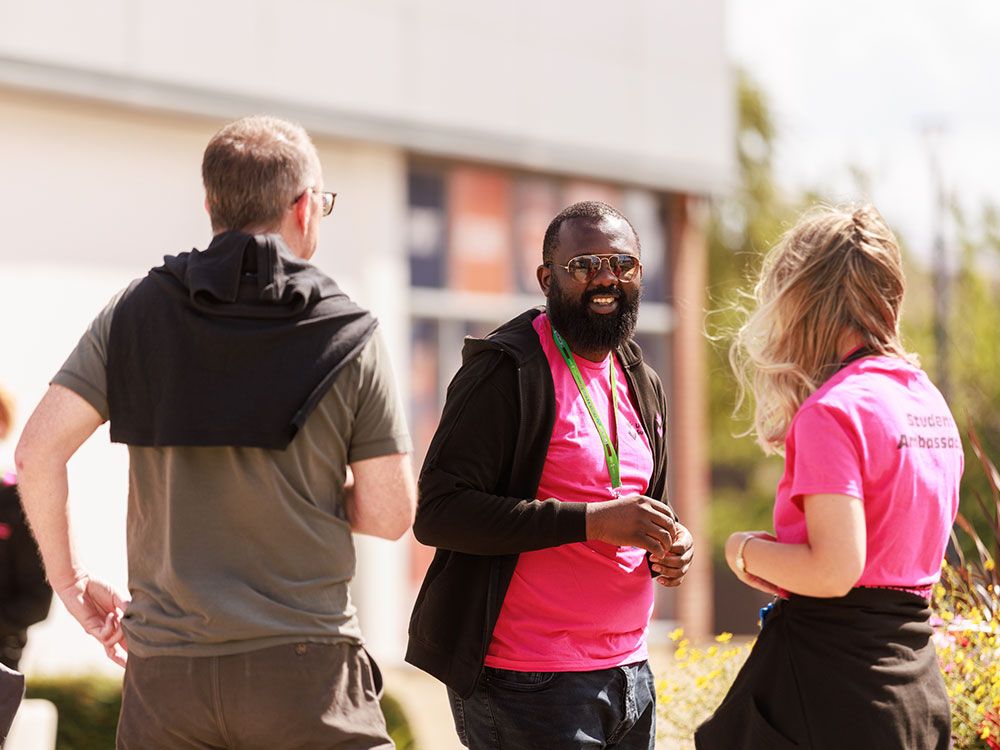 Two student ambassadors speaking to a guest outdoors during an Open Day