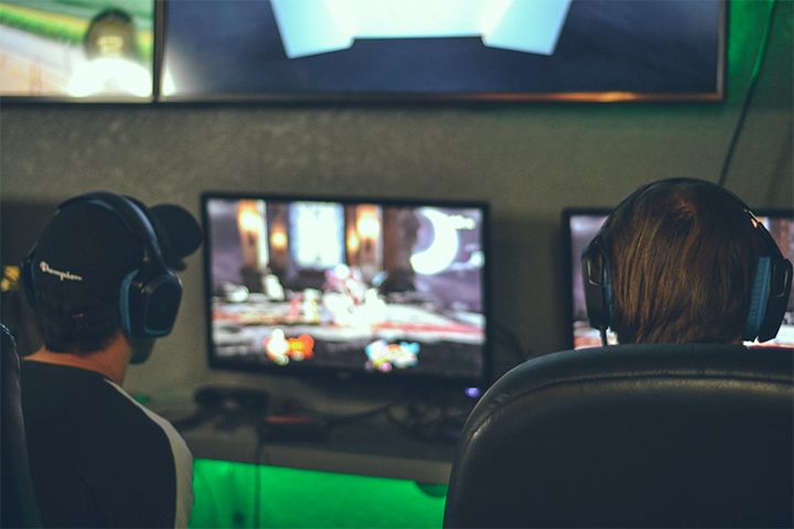 Two people with headsets gaming on PCs