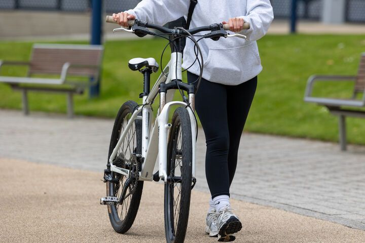 A student walking a bike across campus