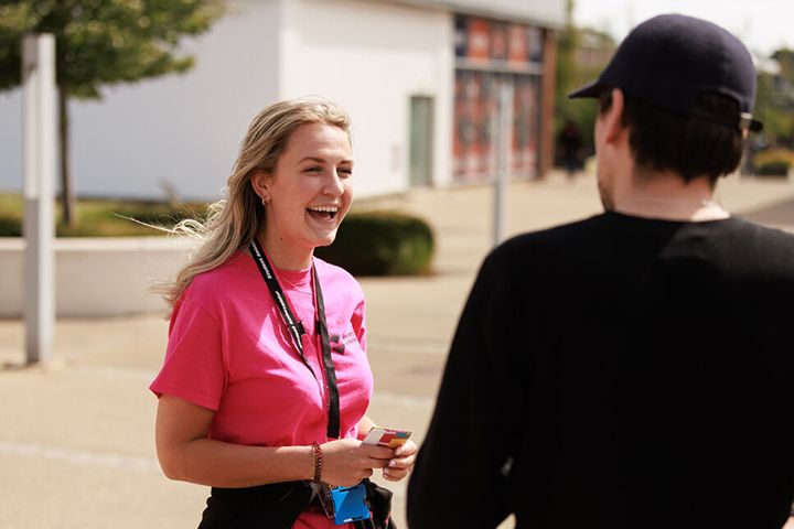 A Student Ambassador smiling at someone on campus