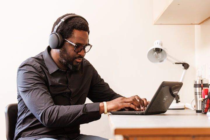 A student typing on a laptop with headphones on