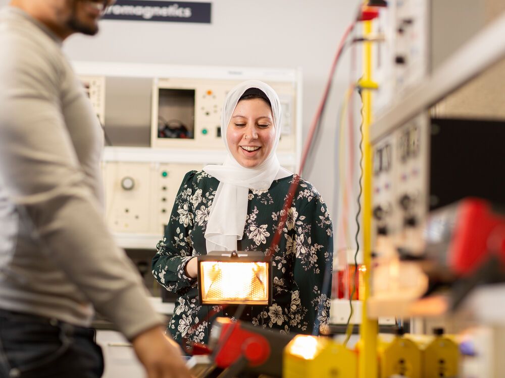 Two engineering students experimenting with equipment in an engineering workshop