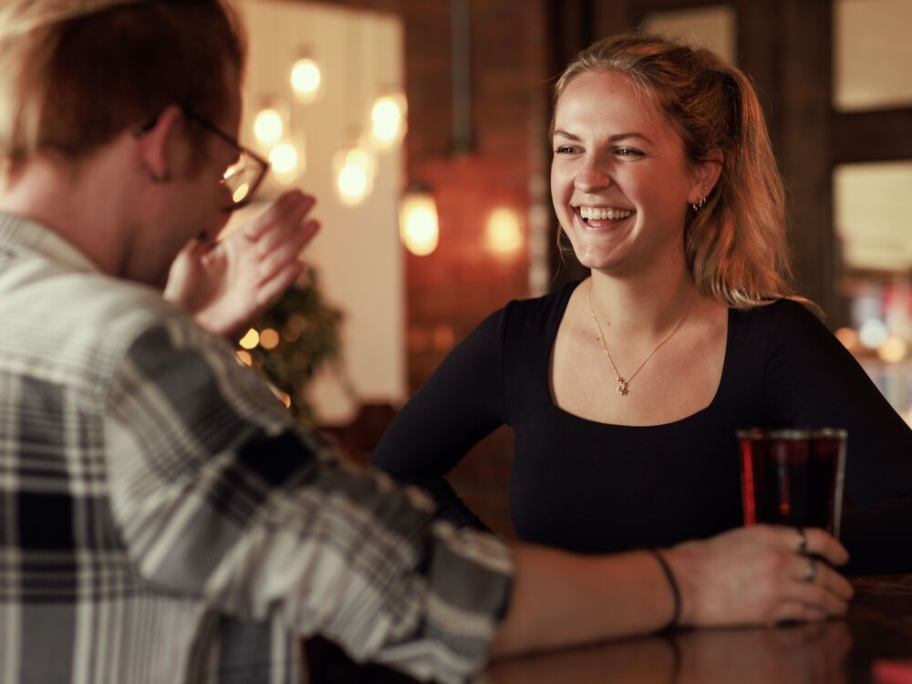 Two students laughing and chatting in a bar while having a drink