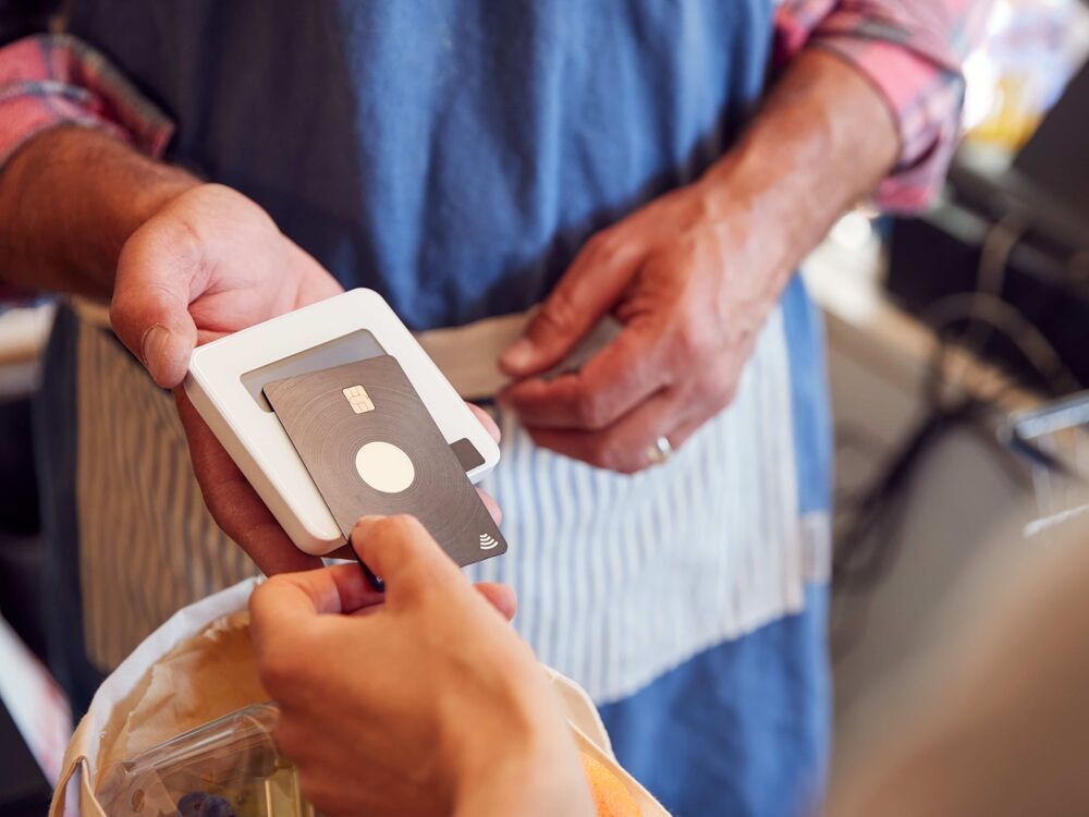 a hand reaching over to tap their contactless card on the card machine