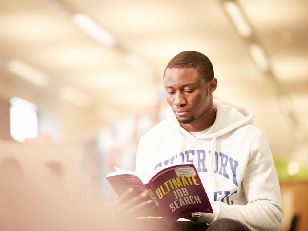 A student reading a book called Ultimate Job Search