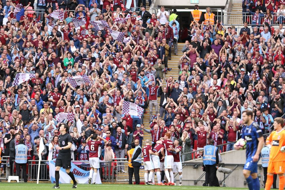 South Shields FC players celebrating a goal in front of fans at Wembley stadium