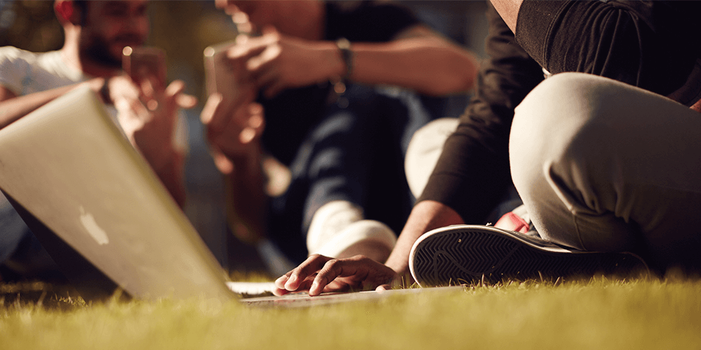 student working on grass with laptop