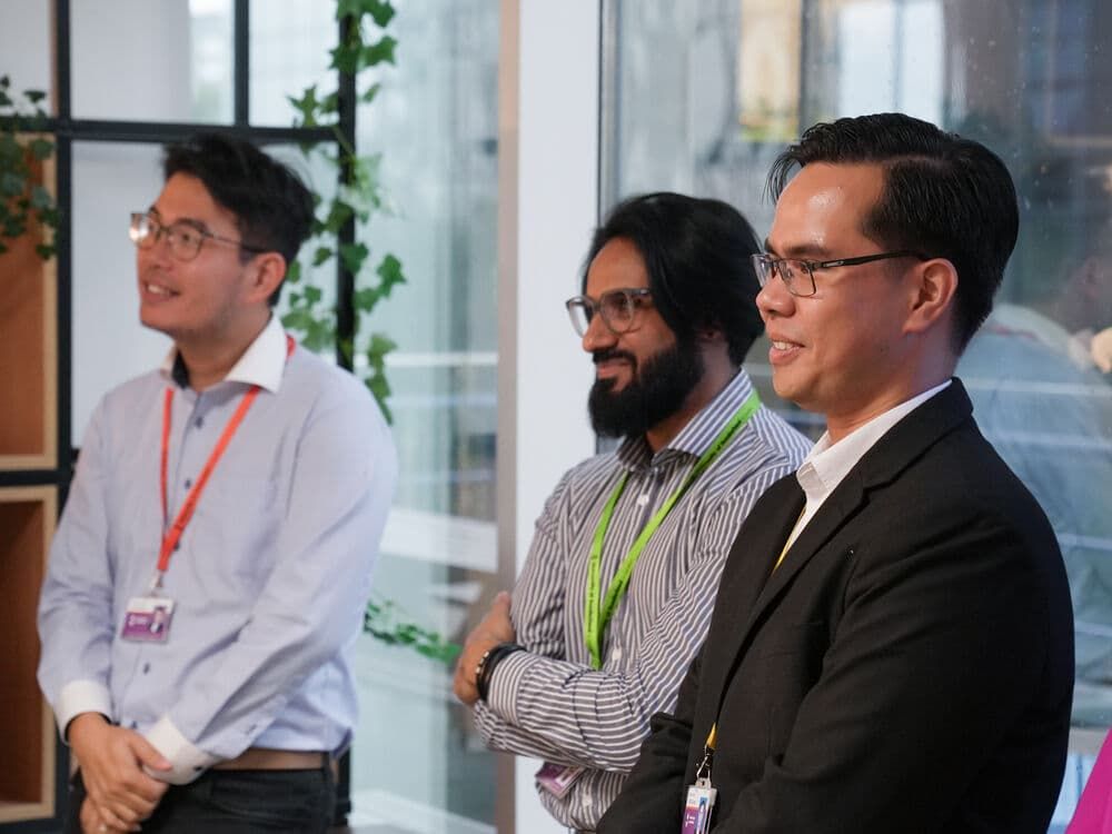 Three academics standing together smiling and listening