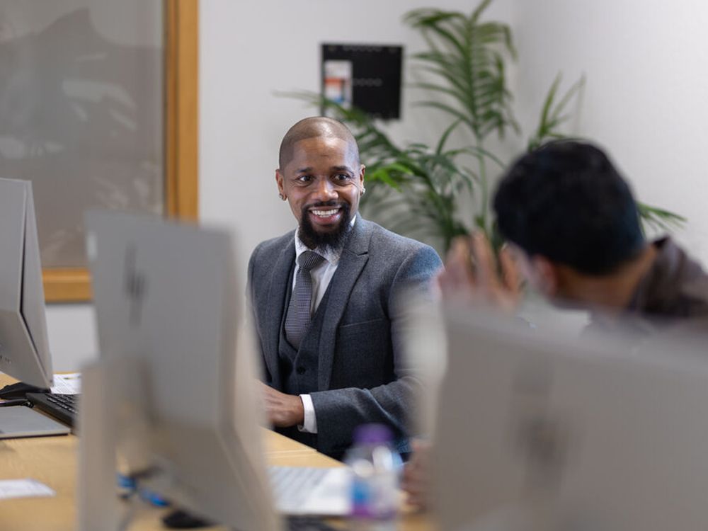 A smiling student sitting at a computer