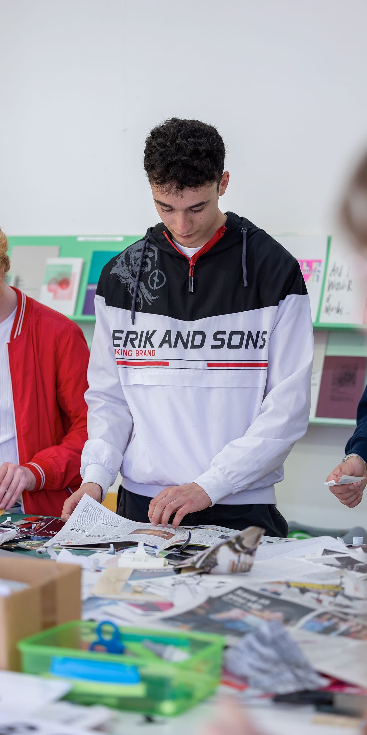 Student looking through magazines scattered on a table in the art room