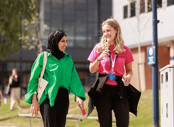 Two people walking across campus in the sun