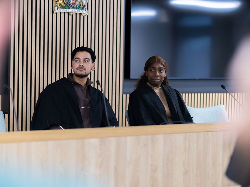 Two students sat together on the bench in the mock law court