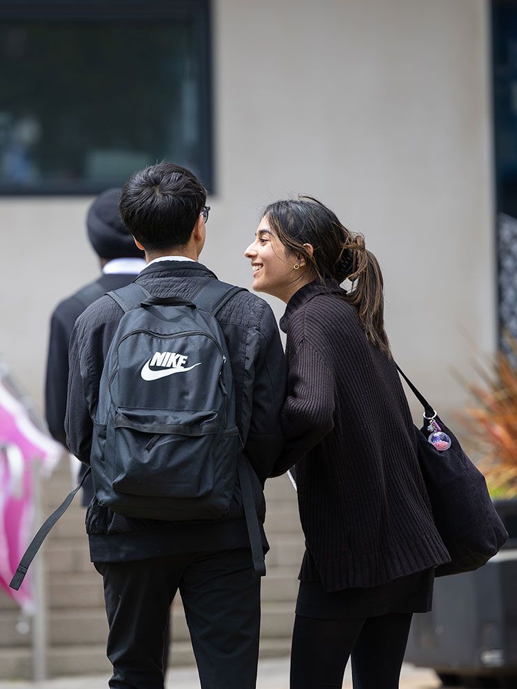 Two school pupils in uniform laughing together on campus