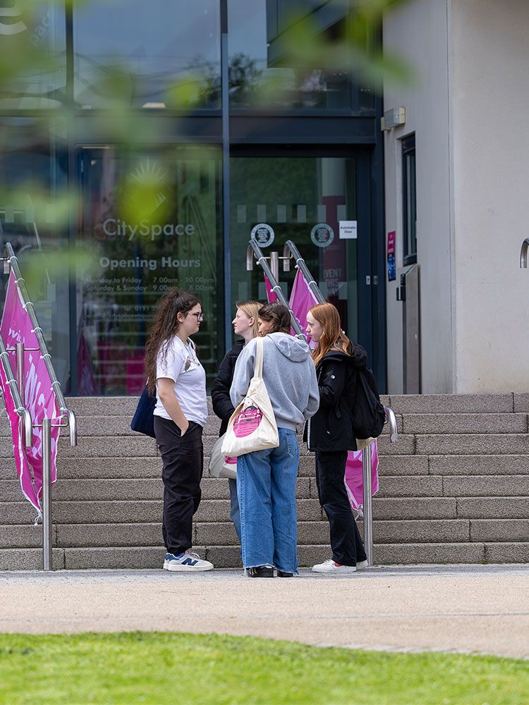 Group of school pupils standing at the stairs to CitySpace talking to each other