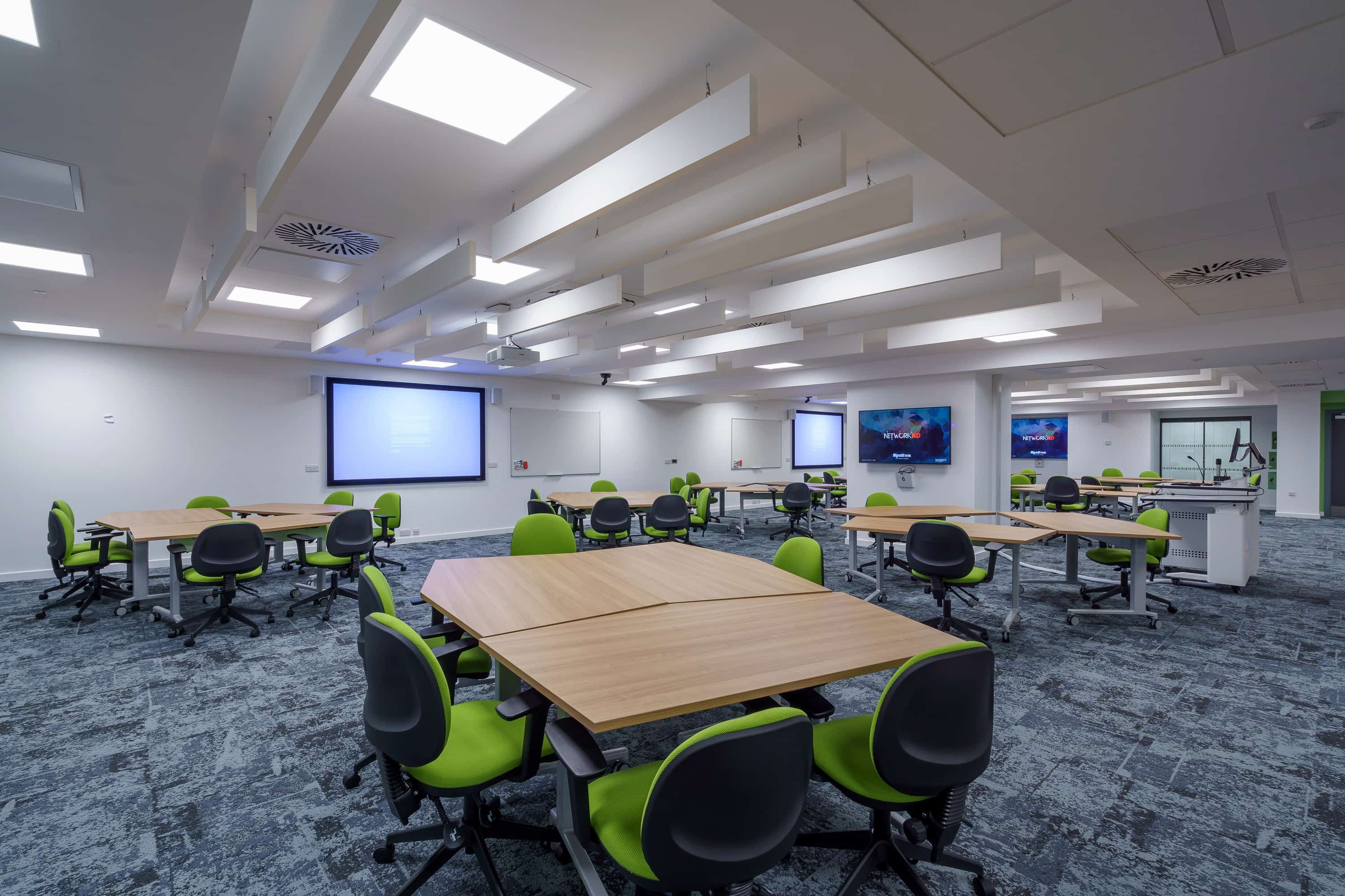 A classroom with tables and chairs and interactive screens in Murray Health