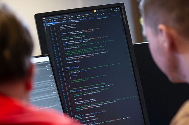 A close up of two students looking at code on a screen