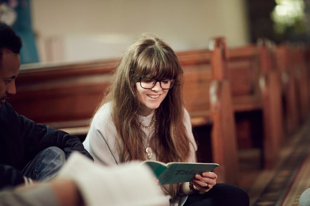 A student reading from a religious book in a church smiling