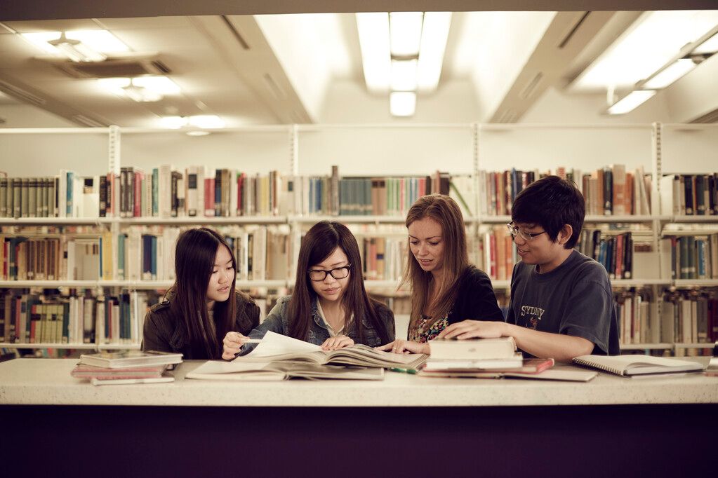 A group of students all looking at the same book on a desk