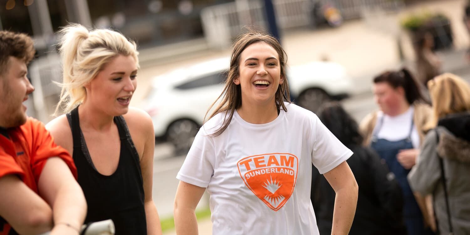 A student wearing a Team Sunderland t-shirt looking joyful