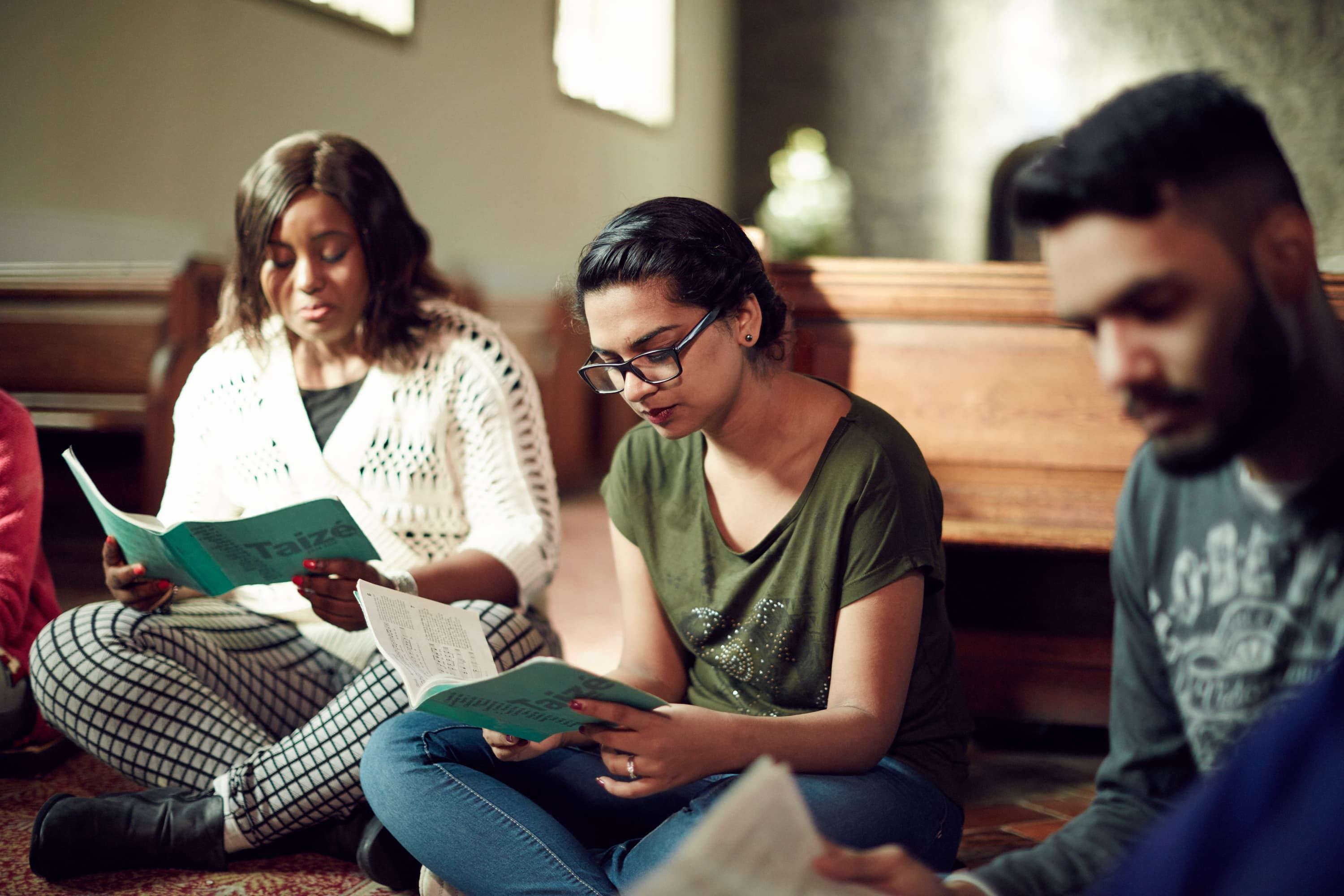 three students in a church sitting down reading