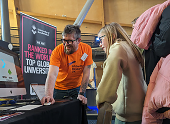 An academic showing a school pupil some data on the computer at a conference