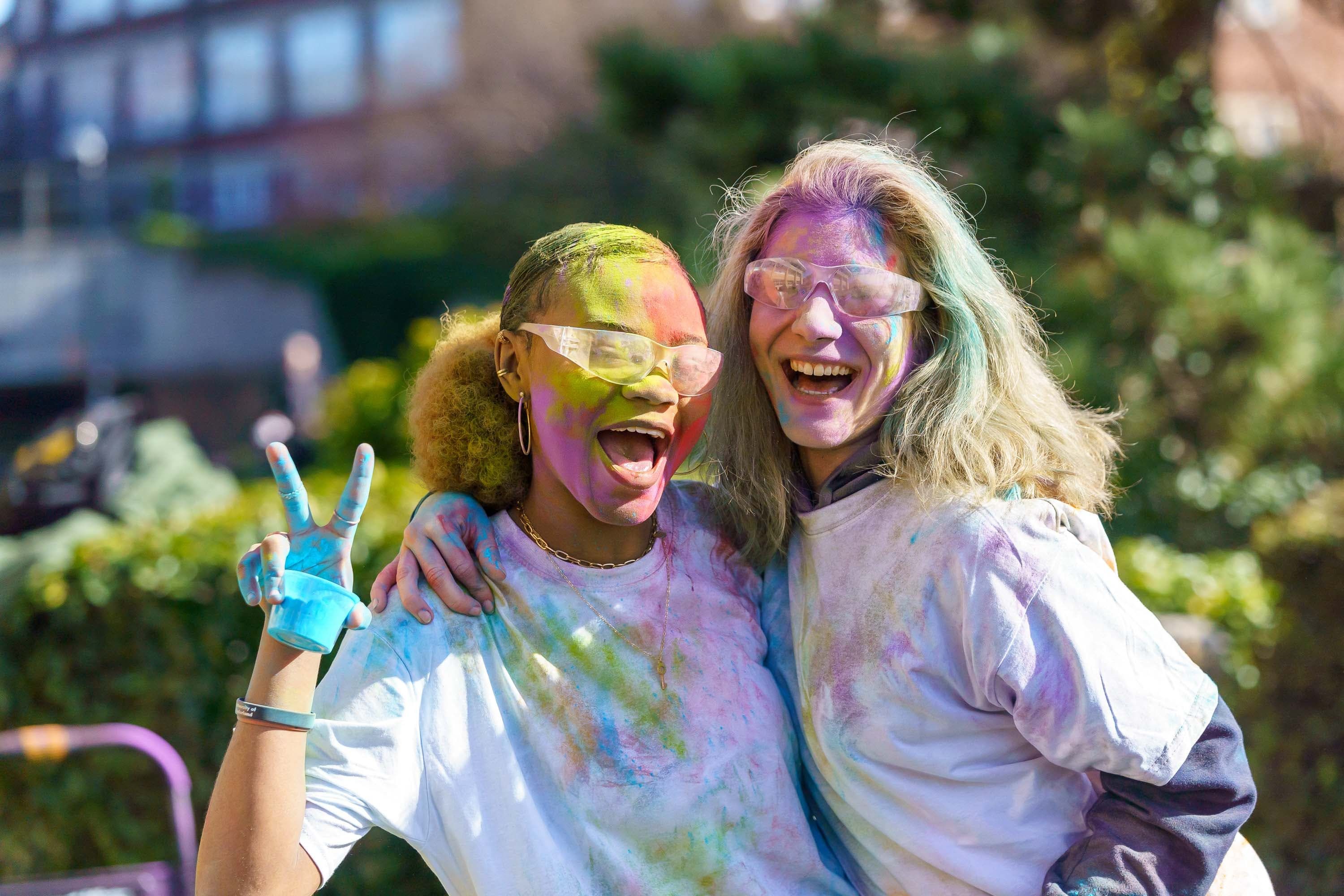 Students posing covered in colourful dust with goggles on and white t-shirts