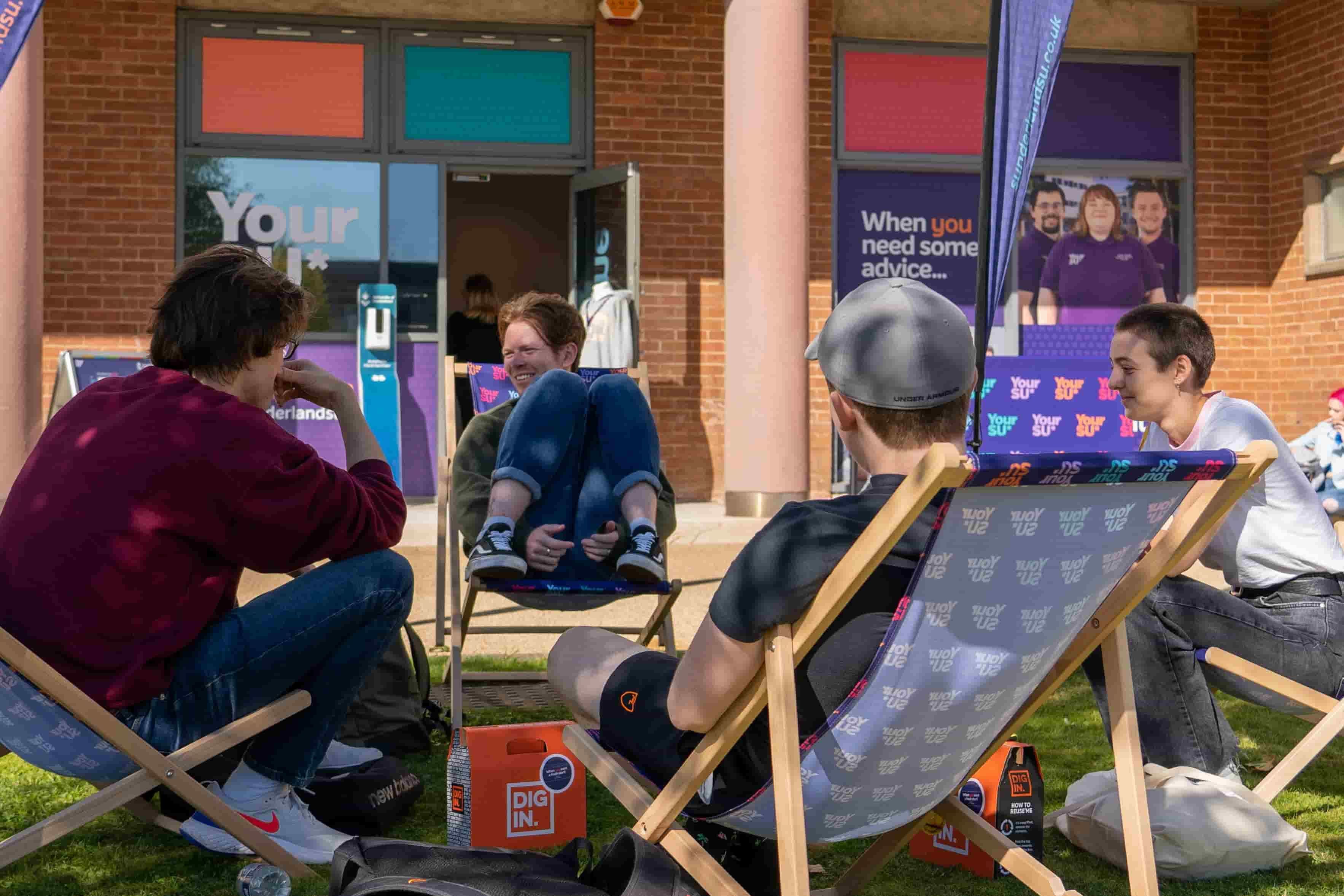 A group of students sitting outside on deck chairs in the sunshine